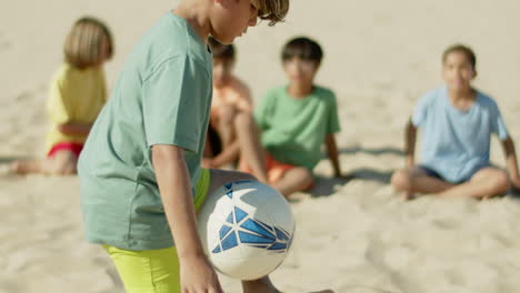 Slow-motion-of-boy-kicking-soccer-ball-with-feet-on-beach